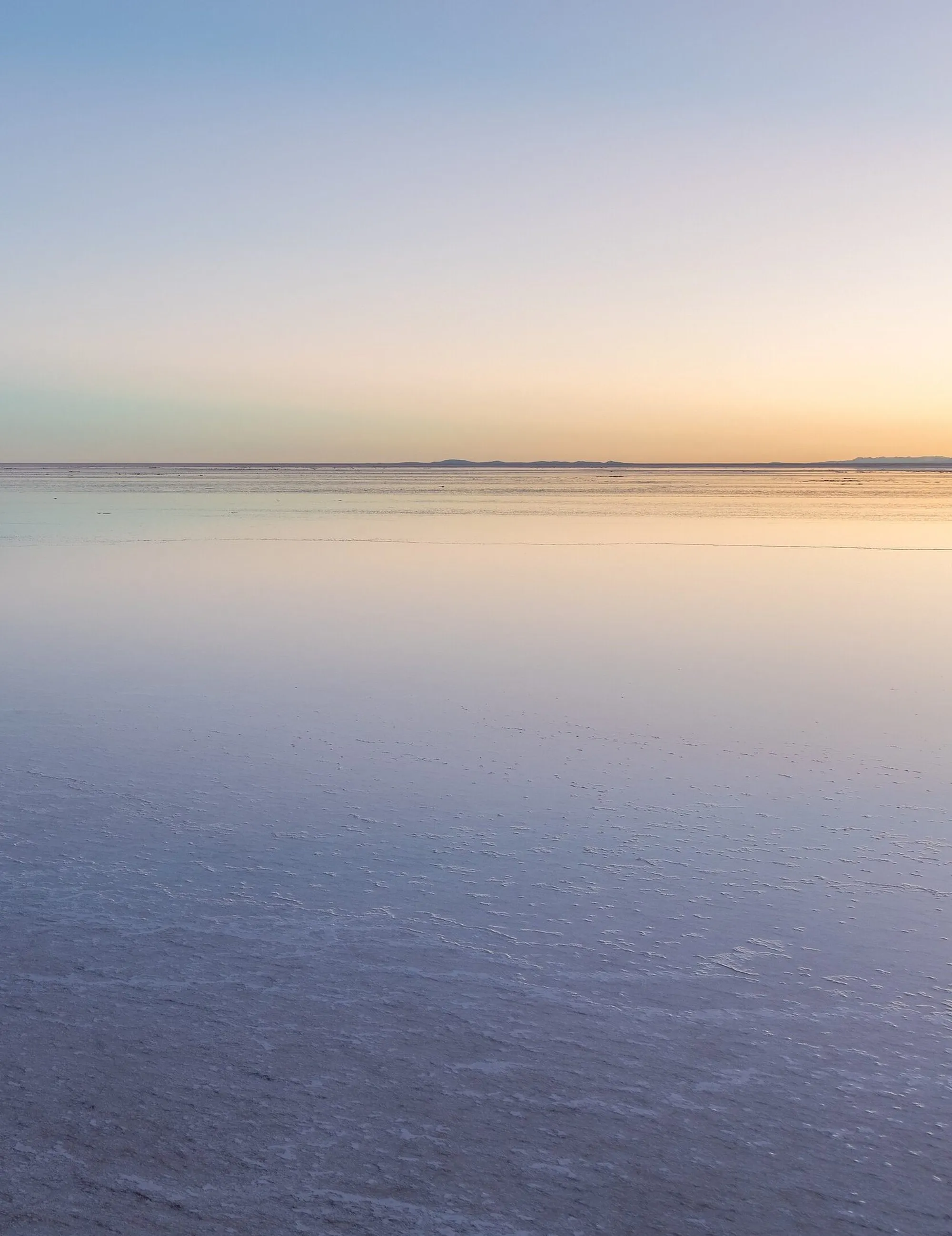 El salar de Uyuni al atardecer, con el cielo reflejado en una lámina de agua sobre la sal.